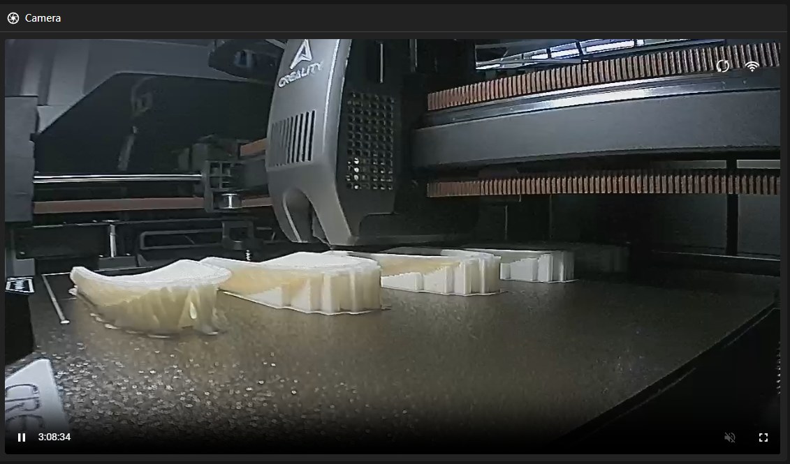 The Creality printhead moving over a plate of parts mid-print.