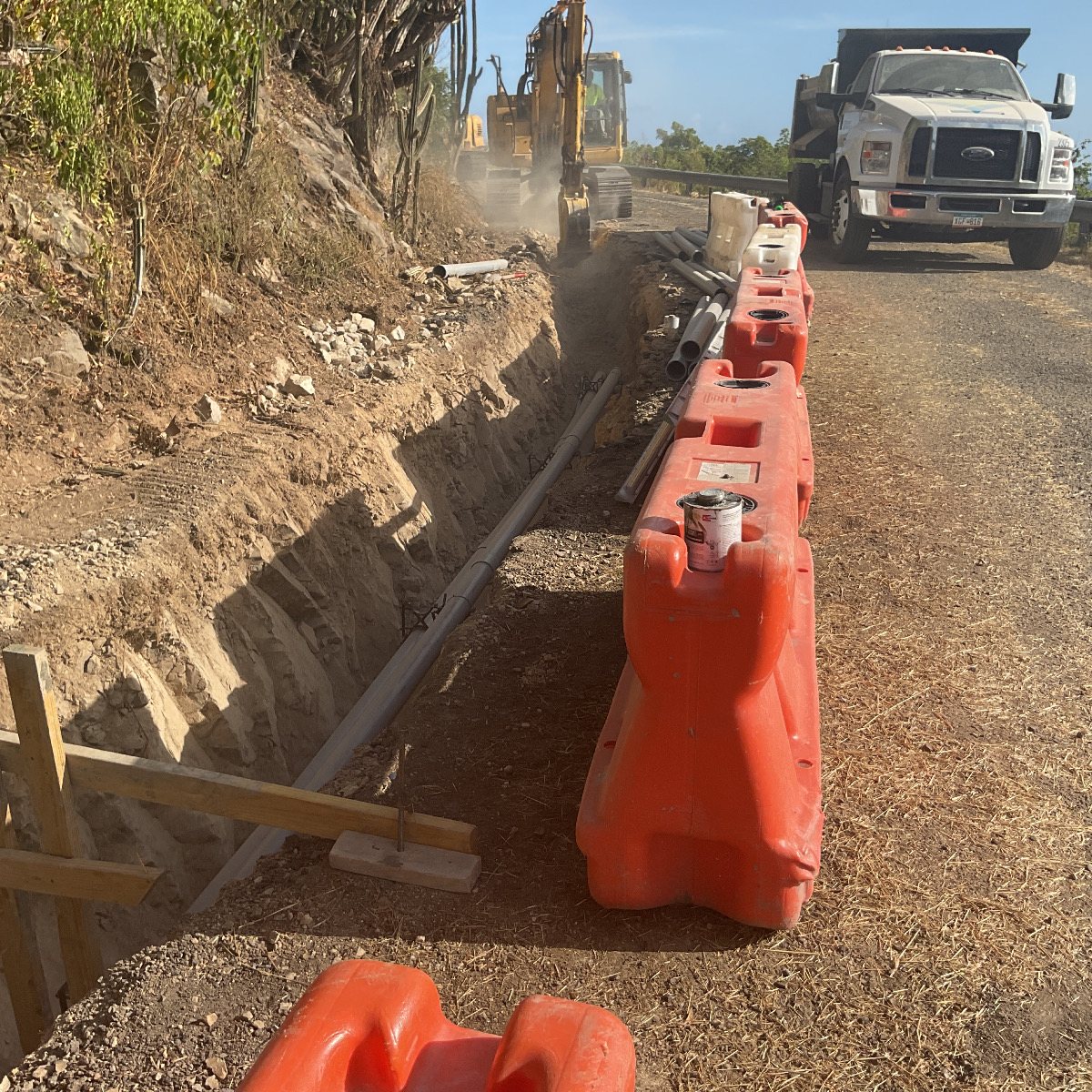 A roadside trench and conduit run on a St. Thomas hillside, part of the WAPA underground electrical program.