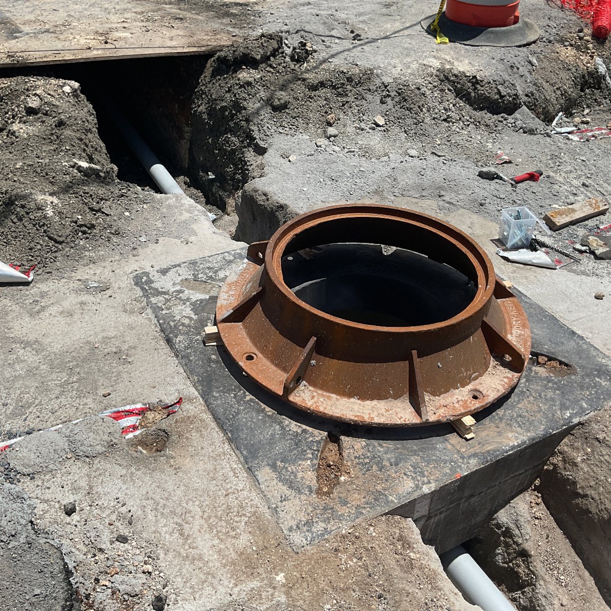 A cast-iron manhole frame set on a concrete vault in the roadway.